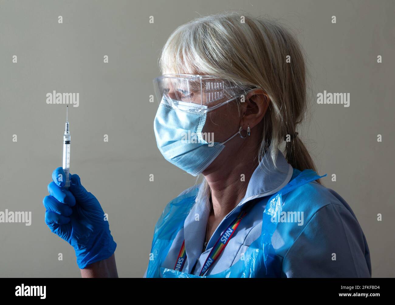 Une infirmière du NHS vérifie une aiguille avec une dose du vaccin Covid.elle administrera ensuite le premier vaccin. Banque D'Images