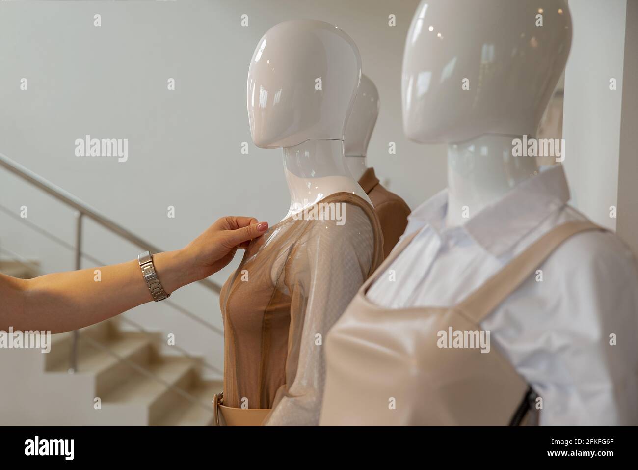 La main d'une femme touche les vêtements d'un mannequin avant de s'installer. Copspace Banque D'Images