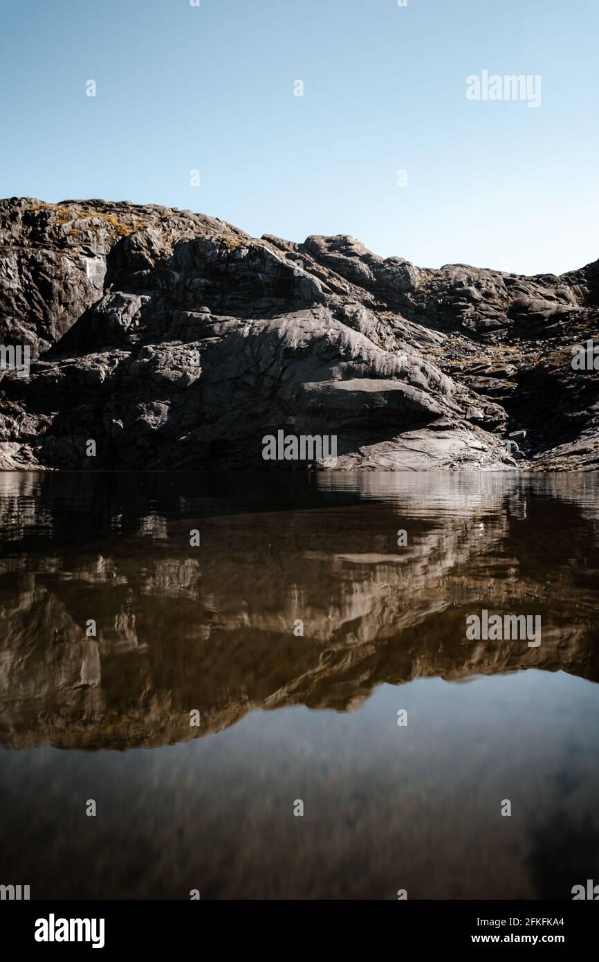 Plan vertical d'une falaise rocheuse naturelle et rugueuse une mer à l'image d'un miroir au lever du soleil Banque D'Images