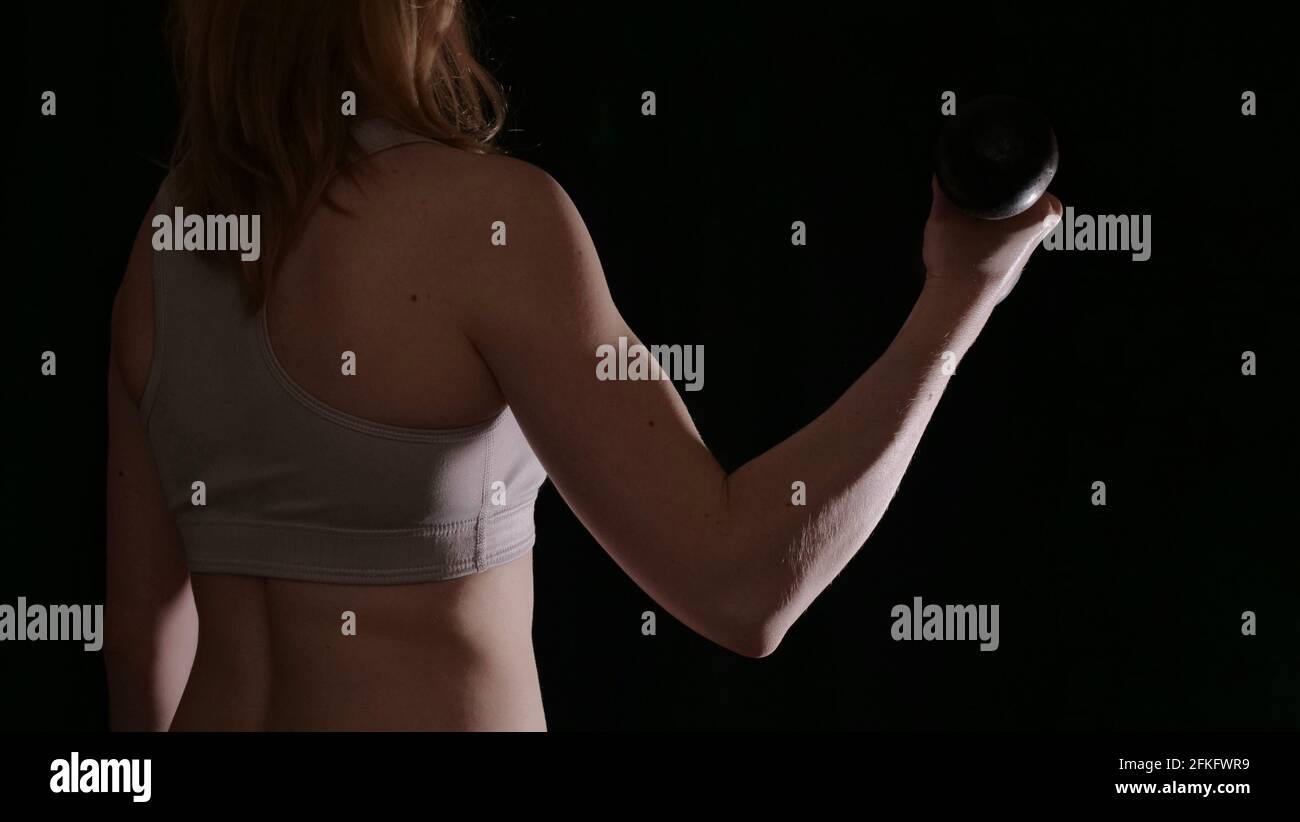 Femme de retour dans les vêtements de sport pendant l'entraînement dans une pose sur un fond noir isolé sans visage. L'image montre les muscles féminins et un beau corps sain Banque D'Images