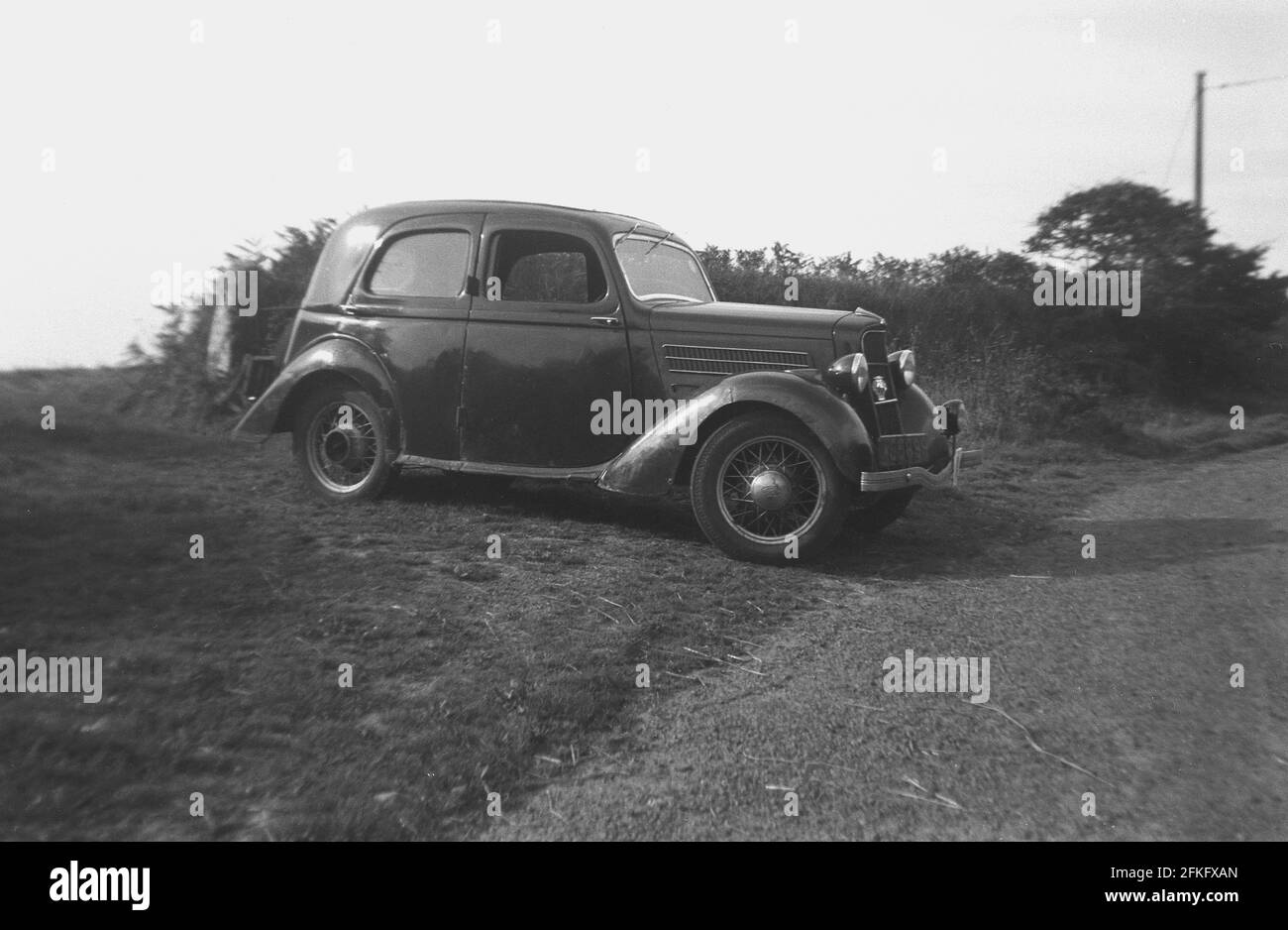 Années 1940, profil historique d'une voiture Ford de l'époque avec des roues métalliques, garée sur une bordure herbeuse ou sur le côté d'une voie de campagne, Angleterre, Royaume-Uni. Banque D'Images
