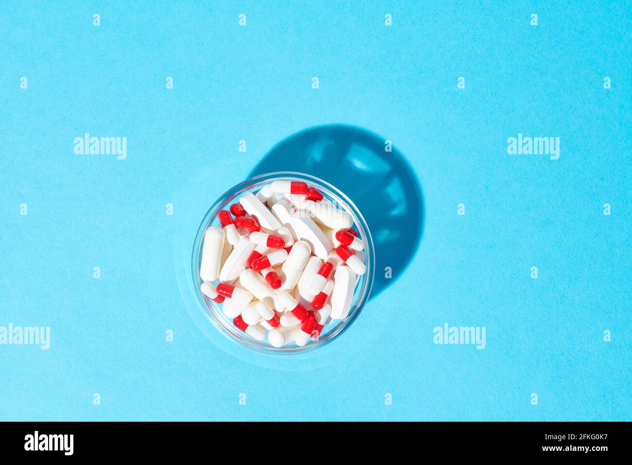 Capsules rouges et blanches et pilules blanches dans un bol Banque D'Images