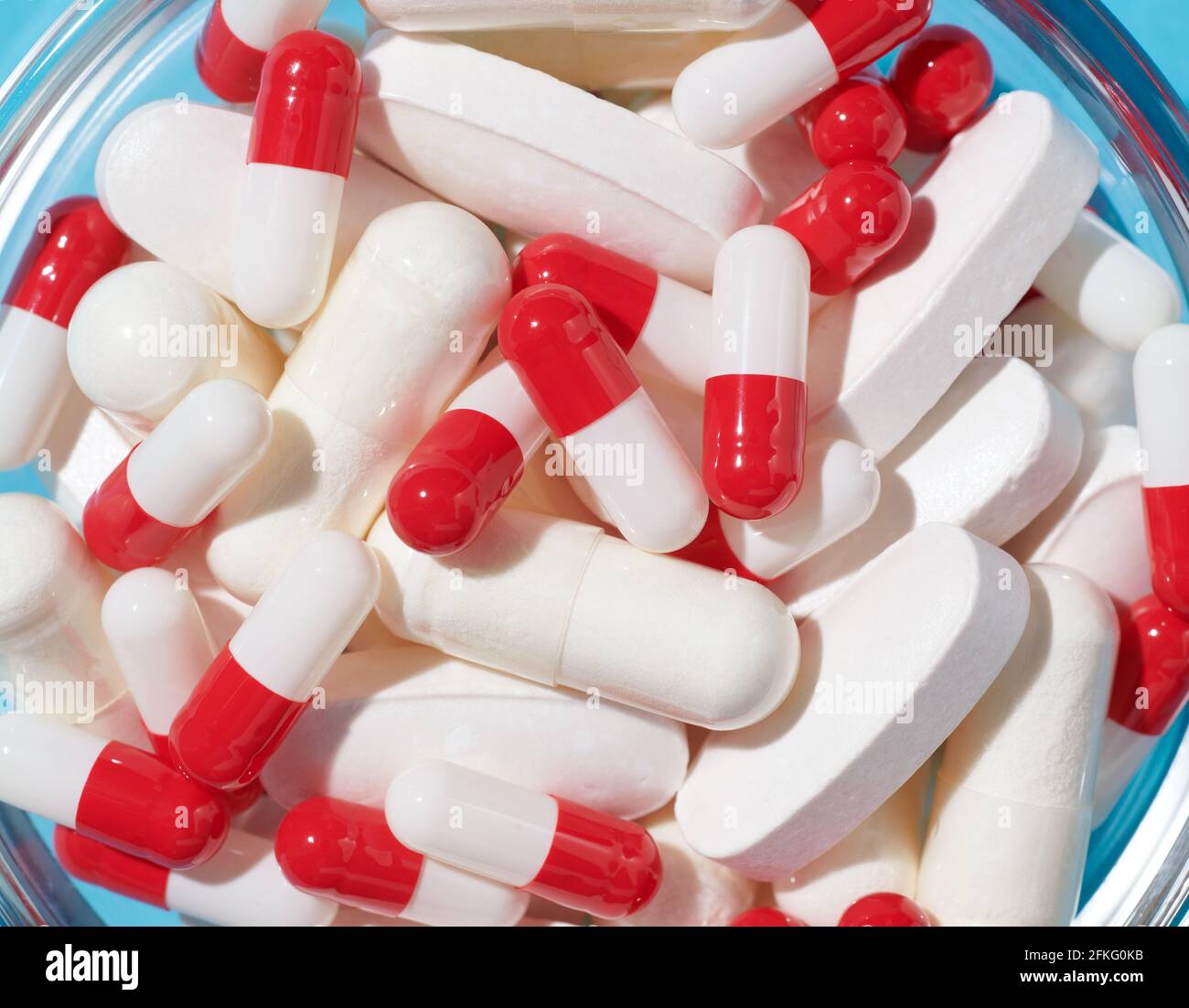Capsules rouges et blanches et pilules blanches dans un bol Banque D'Images