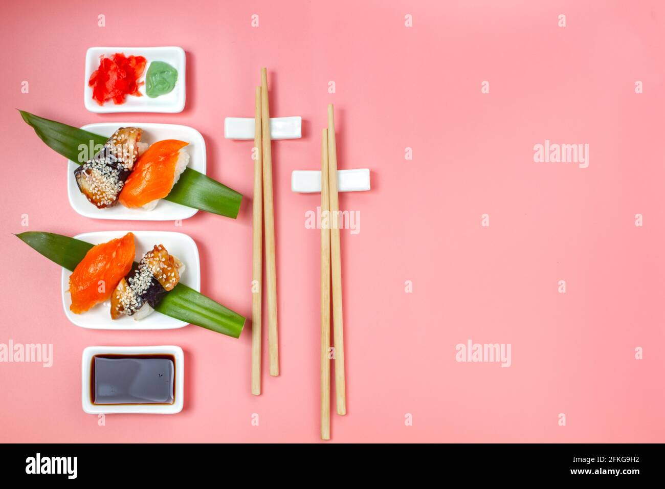 Sushi avec baguettes et sauce soja sur fond rose minimaliste. Banque D'Images
