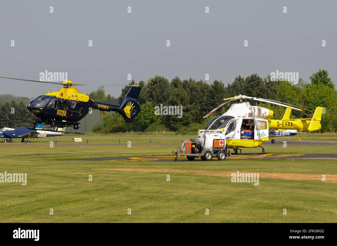 L'hélicoptère G-EHAA d'Essex & Herts Air Ambulance à l'aérodrome d'Earls Colne, Essex, Royaume-Uni, avec l'hélicoptère G-ESEX de la police d'Essex. Base de services d'urgence Banque D'Images