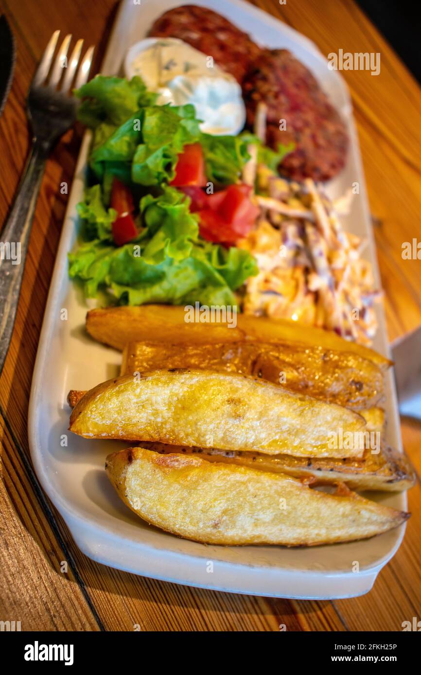 Hamburgers au quinoa et aux graines, avec pommes de terre rôties, salade fraîche et vinaigrette au fromage concombre et à la menthe (plats végétariens). Banque D'Images