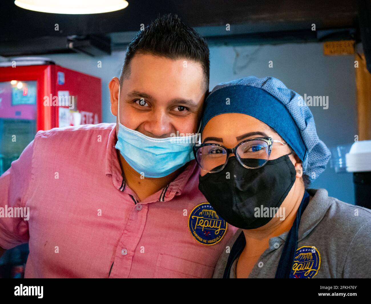 Medellin, Colombie - Mars 28 2021: Jeune latins portant un masque bleu sous son nez à côté d'une femme Brunette portant un uniforme et un masque noir Banque D'Images