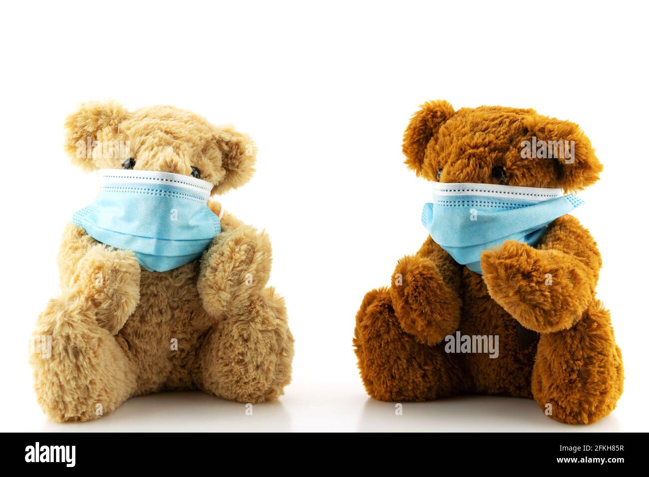 Deux ours en peluche portant un masque de protection, l'ours Teddy est assis dans des masques médicaux bleus sur fond blanc, concept de protection contre les maladies respiratoires Banque D'Images