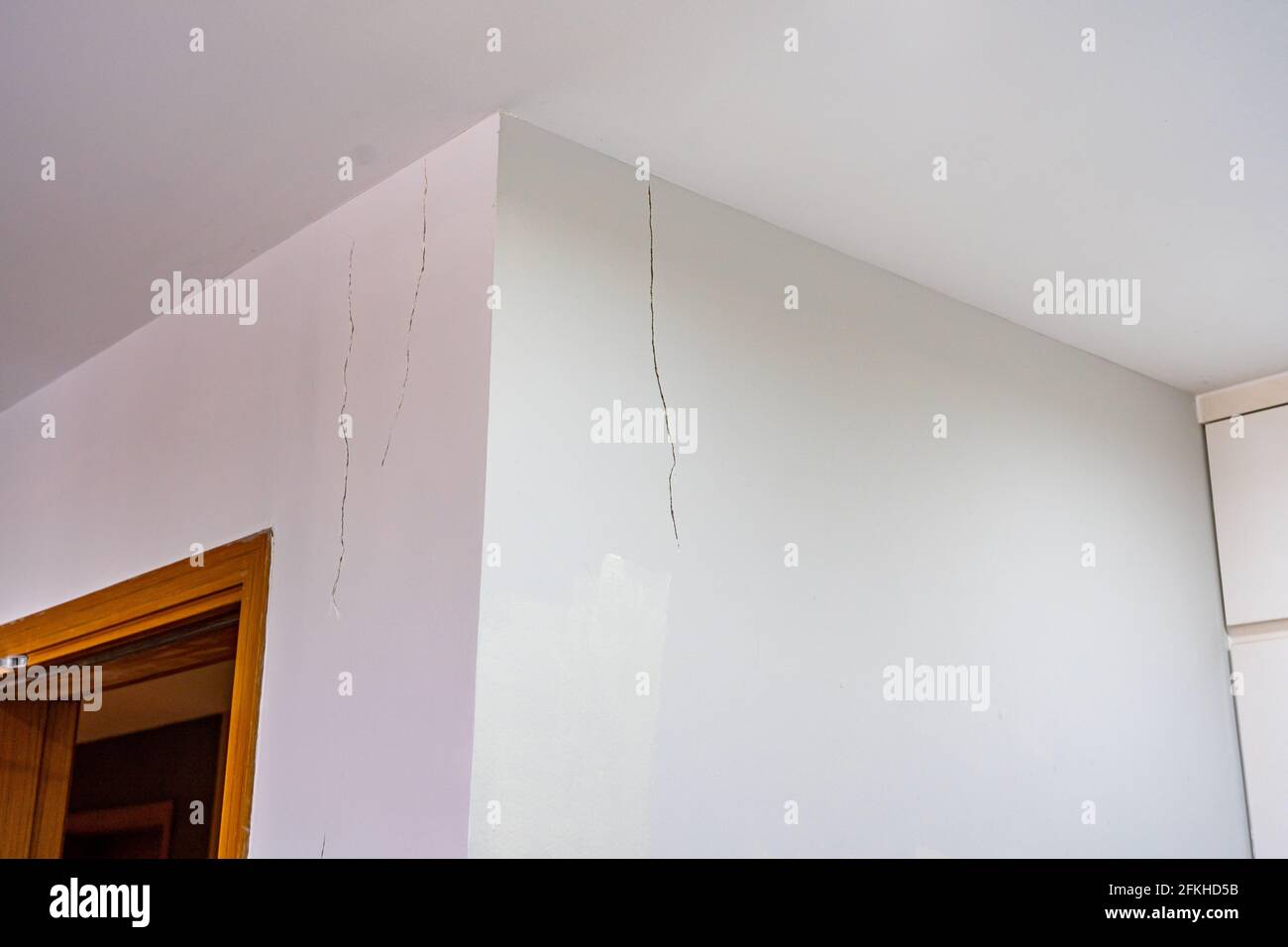 Mur peint en blanc avec des fissures près du plafond Banque D'Images