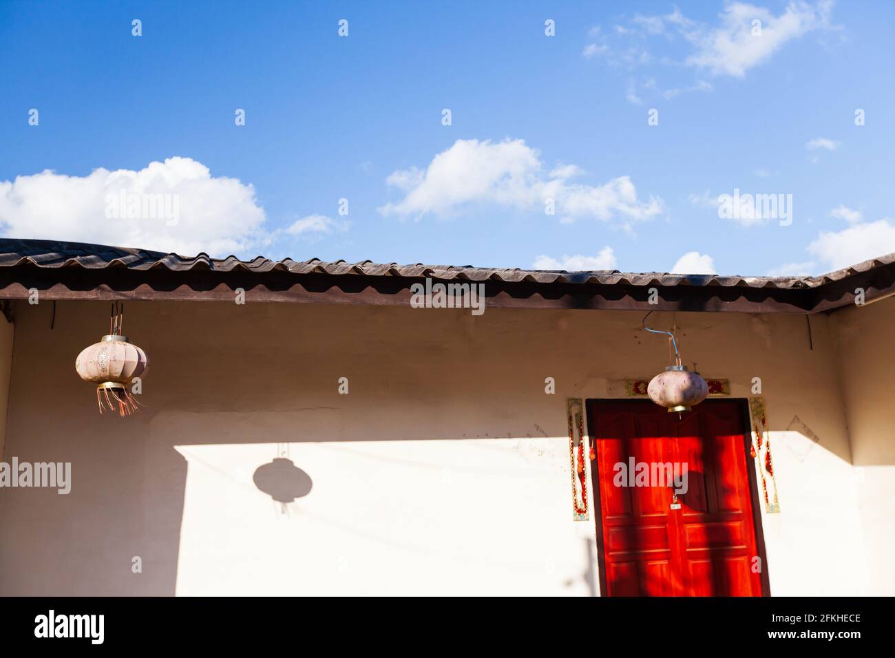 Lever de soleil brillant sur une ancienne maison du Yunnanese, porte rouge contre le mur blanc et ciel bleu dans les fonds. Doi Mae Salong, Chiang Rai, Thaïlande. Banque D'Images Lever de soleil brillant sur une ancienne maison du Yunnanese, porte rouge contre le mur blanc et ciel bleu dans les fonds. Doi Mae Salong, Chiang Rai, Thaïlande. Banque D'Images