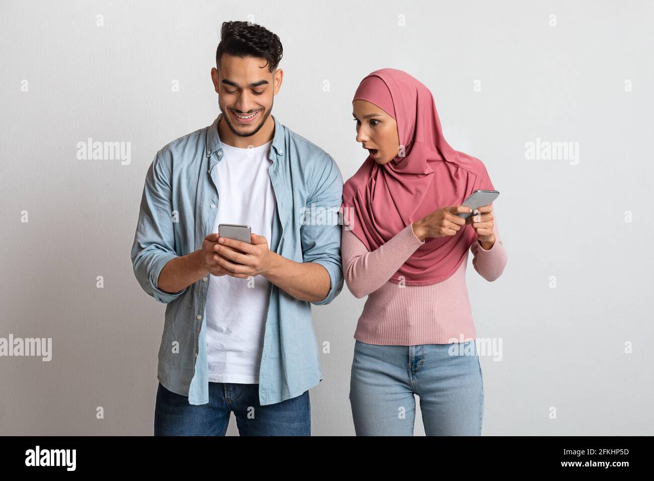 Une femme musulmane jalouse dans le hijab regardant le téléphone mobile de l'ami, souffrant de méfiance Banque D'Images