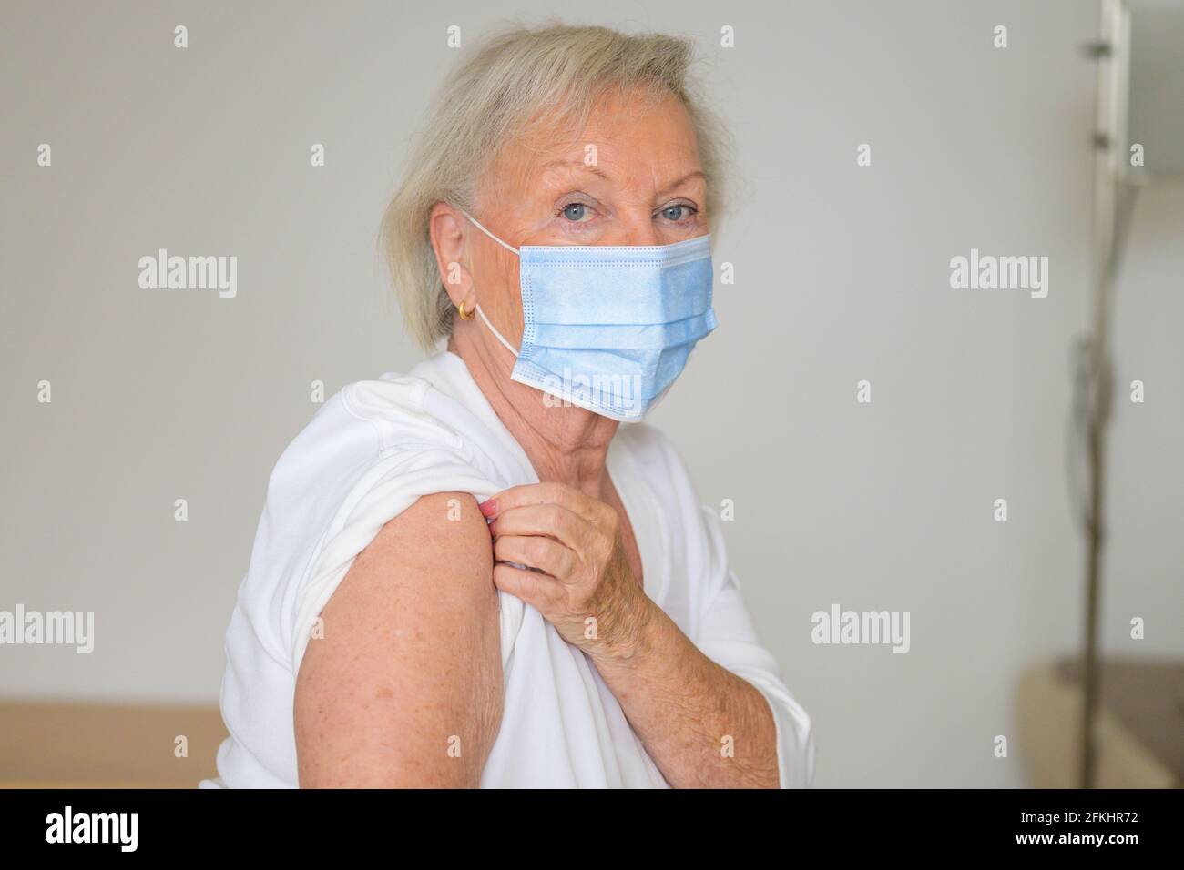 Une dame de haut en haut de sa manche pour prouver qu'elle n'a pas Effets nocifs du vaccin Covid-19 après avoir été vacciné contre le coronavirus pendant la pan Banque D'Images