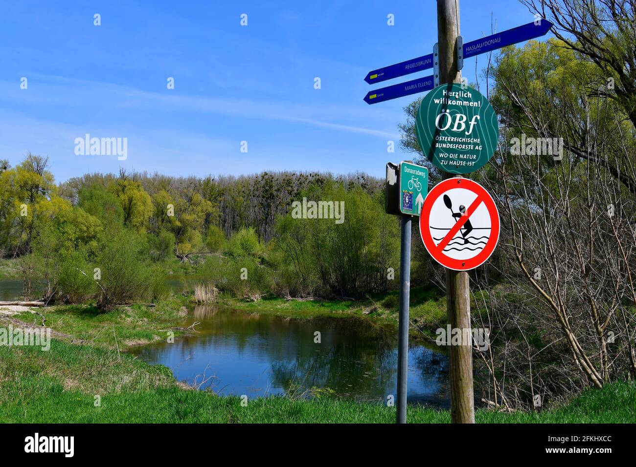 Haslau, Autriche - 24 avril 2021 : paysage avec lac oxbow et panneau indiquant la distance et un panneau sur la piste cyclable ainsi qu'un iti interdit Banque D'Images
