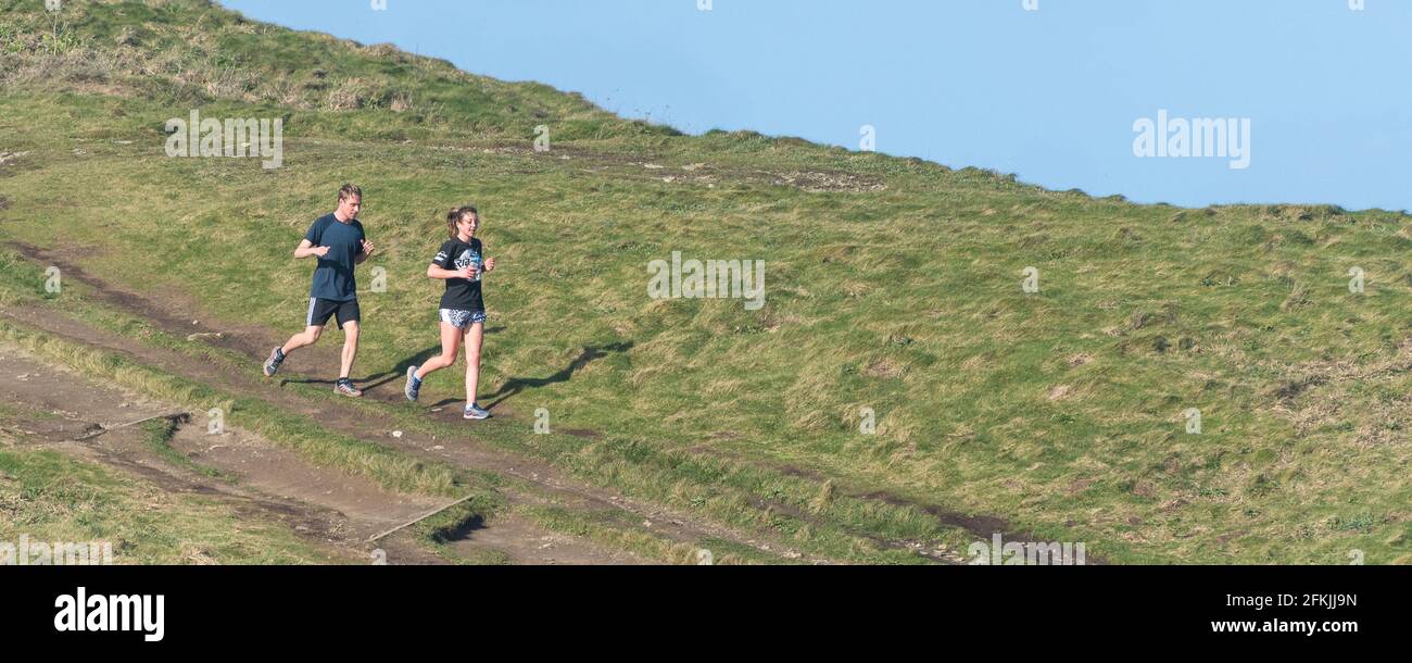Image panoramique d'un coureur mâle et d'une femelle sur un sentier de Towan Head à Newquay, en Cornouailles. Banque D'Images