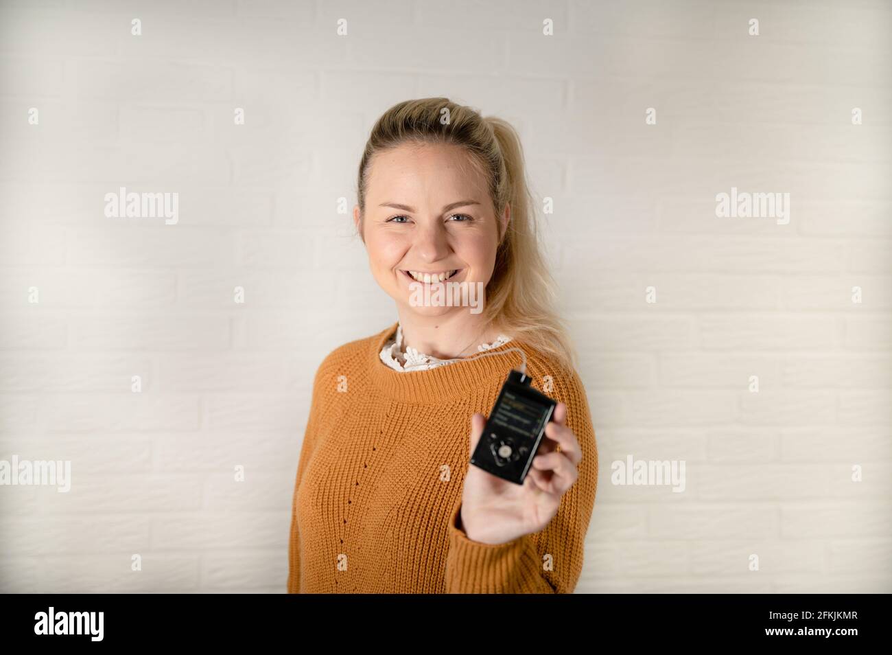 Belle femme blonde tenant sa pompe à insuline - traitant le diabète avec la technologie Banque D'Images