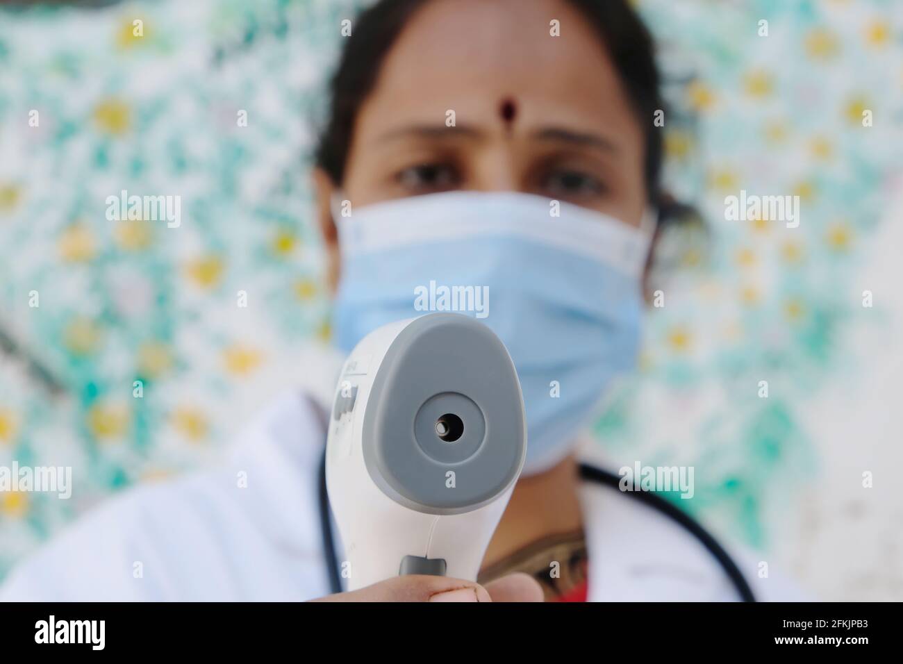 Un médecin indien tenant un thermomètre infrarouge médical pour