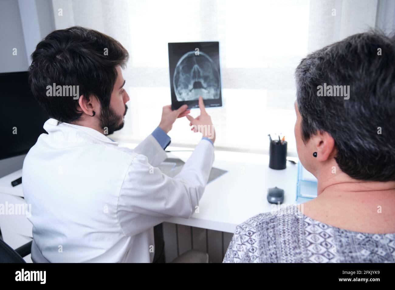 Jeune médecin examinant les rayons X du crâne, les sinus avec une patiente adulte. Radiographie d'une tête. Banque D'Images