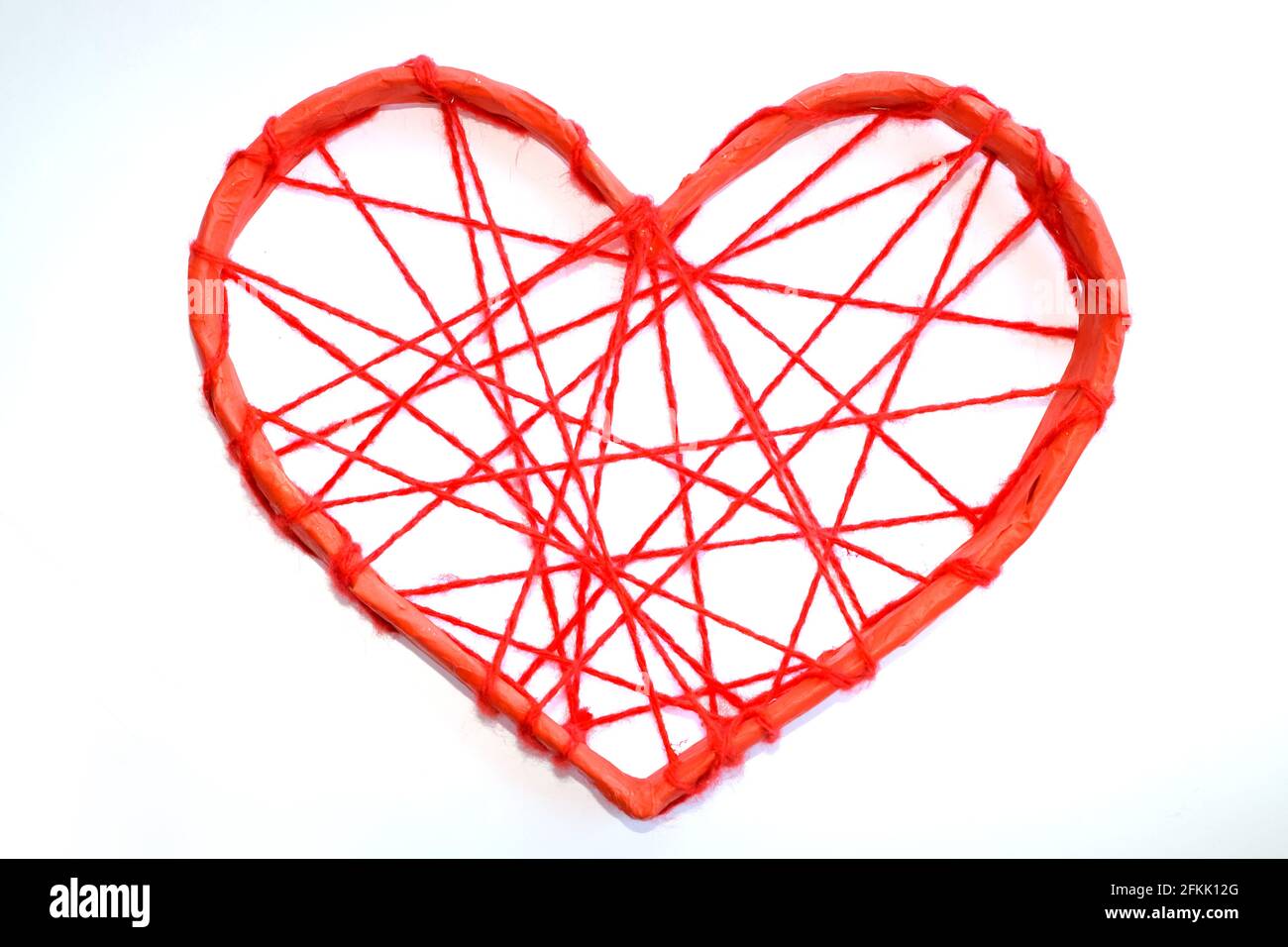 Un coeur en papier attaché avec des fils rouges. Cœur sur fond blanc. Banque D'Images
