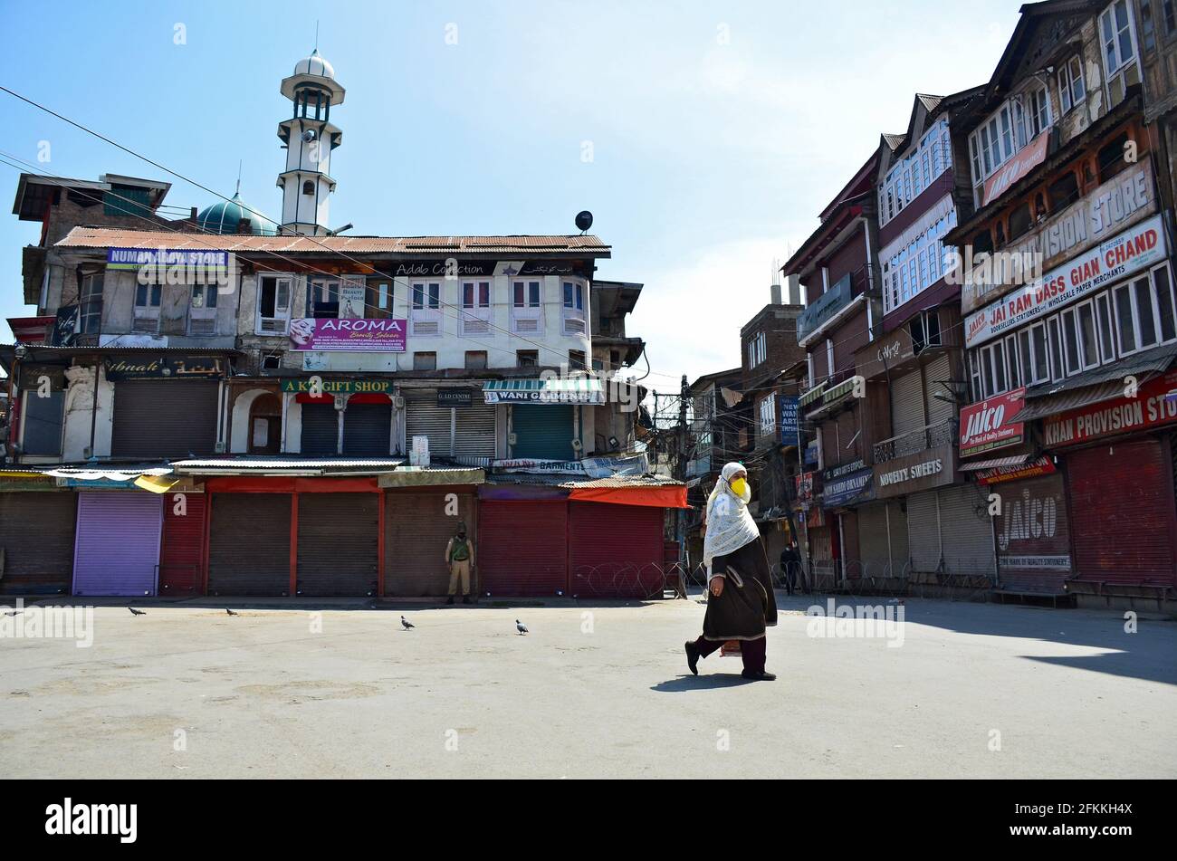 Une femme porte un masque facial lorsqu'elle traverse une route déserte lors d'un verrouillage imposé par les autorités suite à l'augmentation des cas de coronavirus à Srinagar. Compte tenu de l'augmentation rapide des cas de Covid-19 dans la deuxième vague de la pandémie, le gouvernement de Jammu-et-Cachemire a prolongé le confinement actuel de la COVID-19 jusqu'en mai 06. Dimanche, Jammu-et-Cachemire a été témoin de la plus forte augmentation d'un jour de 3832 cas de COVID-19 avec 47 décès, le plus grand nombre de décès dans l'État depuis l'épidémie de coronavirus l'an dernier. Pendant ce temps, l'Inde a signalé 392,488 cas de coronavirus et plus de 3,689 cas de deat Banque D'Images