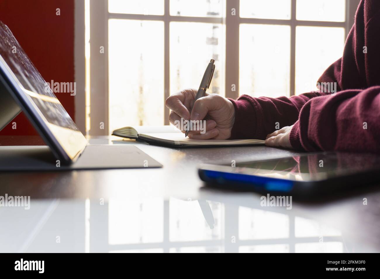 Un étudiant qui écrit des notes tout en ayant une conférence en ligne Banque D'Images