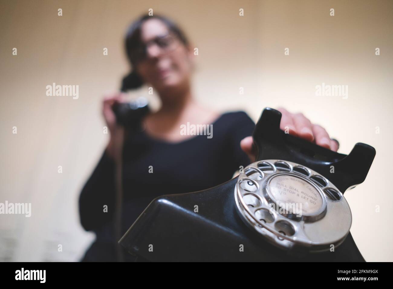 Une femme parle par un vieux téléphone Banque D'Images