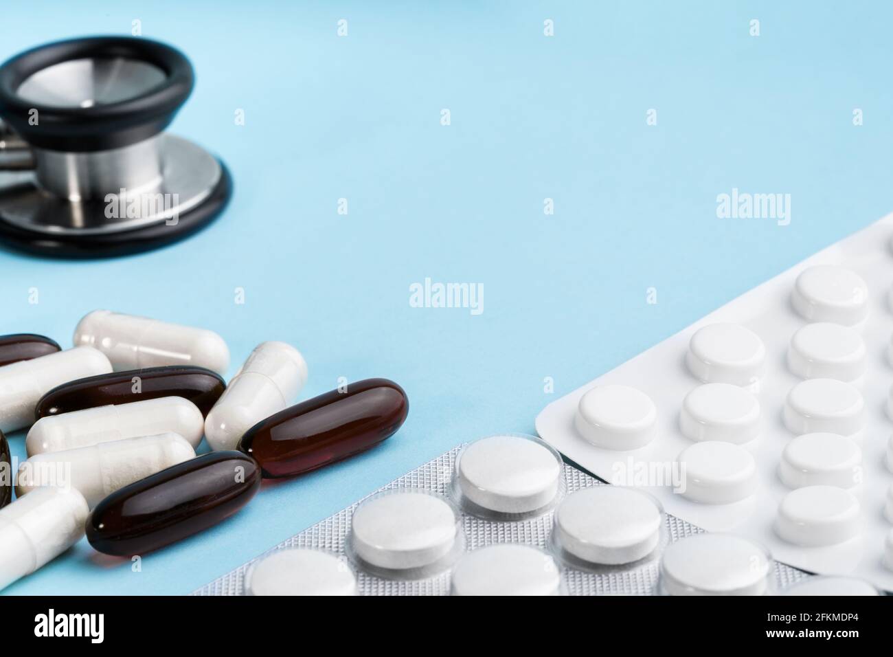 Capsules brunes et blanches assorties, stéthoscope, blister isolé sur fond bleu. Compléments nutritionnels pour la perte de poids et l'énergie, aides alimentaires Banque D'Images