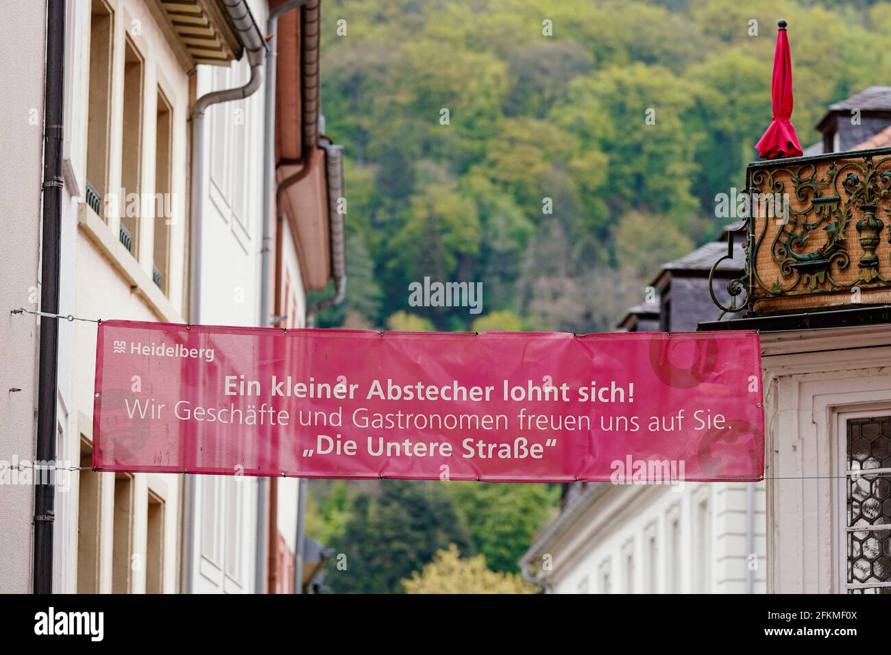 Heidelberg, Allemagne. 29 avril 2021. Une bannière avec l'inscription 'UN petit détour vaut la peine! Nous magasins et restaurateurs nous réjouissons de vous voir. 'La rue inférieure' est suspendue sur la rue principale, une zone piétonne et une rue commerçante dans le centre-ville, entre deux murs de maisons. (À dpa: 'Le groupe de travail Heidelberg lutte contre les postes vacants dans le centre-ville') Credit: Uwe Anspach/dpa/Alamy Live News Banque D'Images