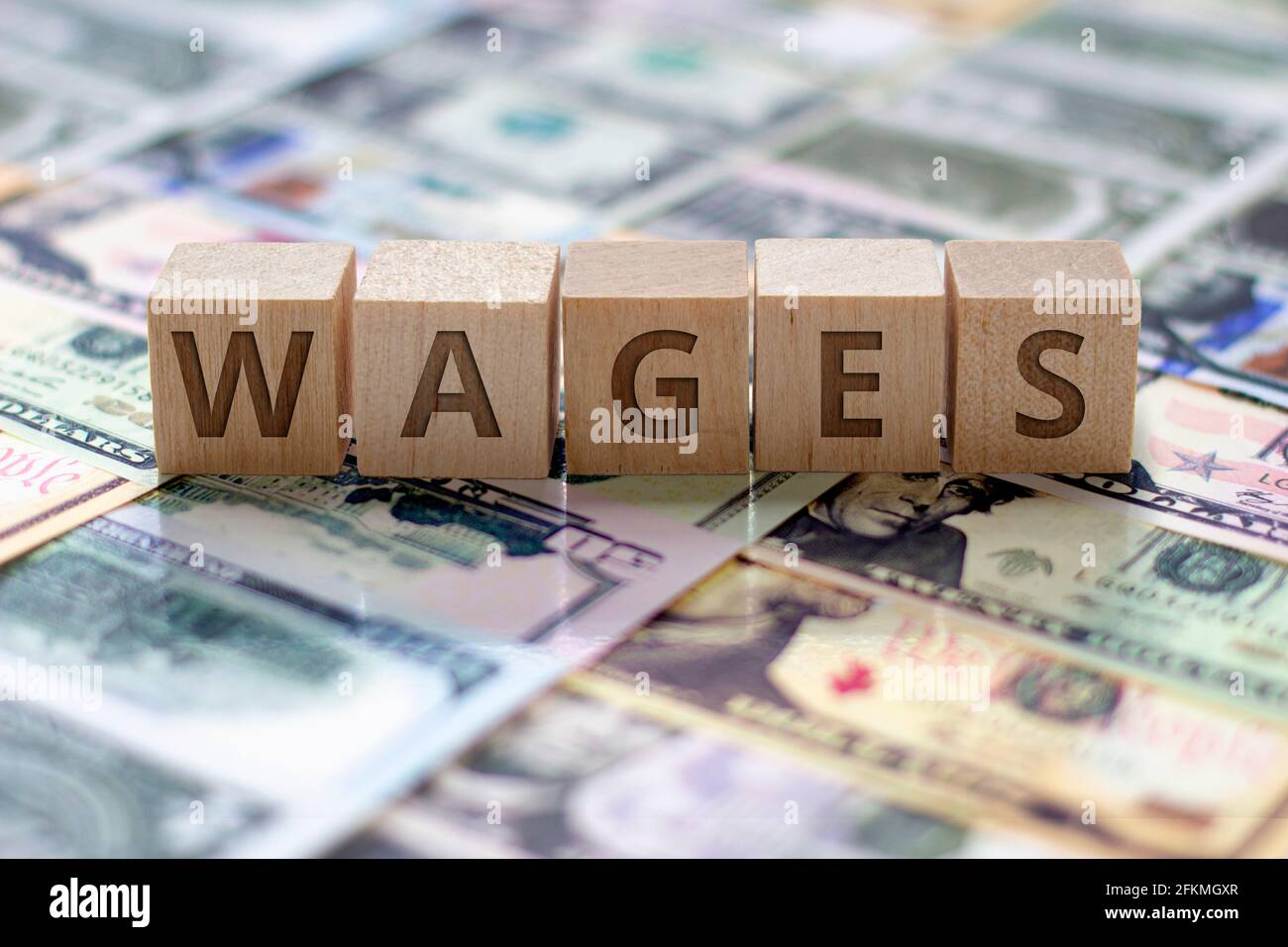 Blocs en bois avec le mot «salaires» sur les notes de dos de factures sur l'arrière-plan. Concept: Salaires et salaires Banque D'Images