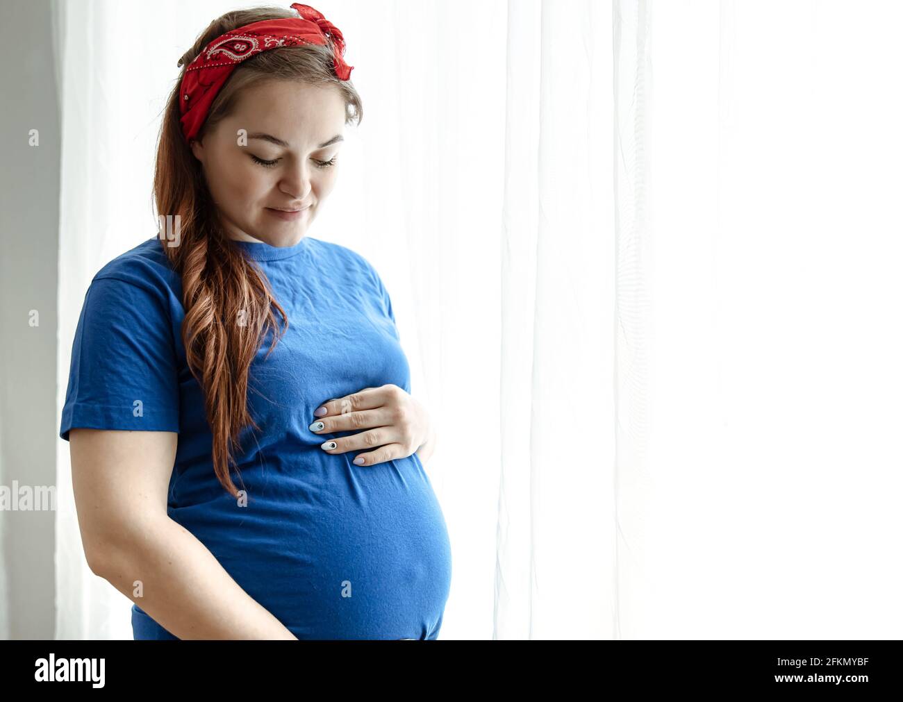 Belle femme enceinte dans les derniers mois de la grossesse dans les  vêtements à la maison près de la fenêtre Photo Stock - Alamy
