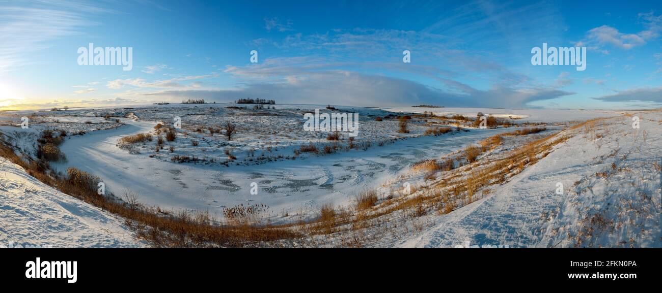 Paysage ensoleillé panoramique au début du printemps. Belle vue sur la rivière gelée et les champs enneigés pendant le matin ensoleillé de mars. Banque D'Images