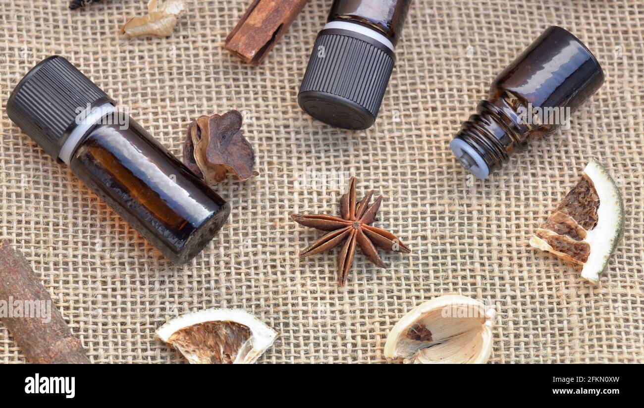 vue de dessus sur les bouteilles d'huile essentielle avec bâton de cannelle, badian et fruits secs avec coquille sur un fond de tissu naturel Banque D'Images