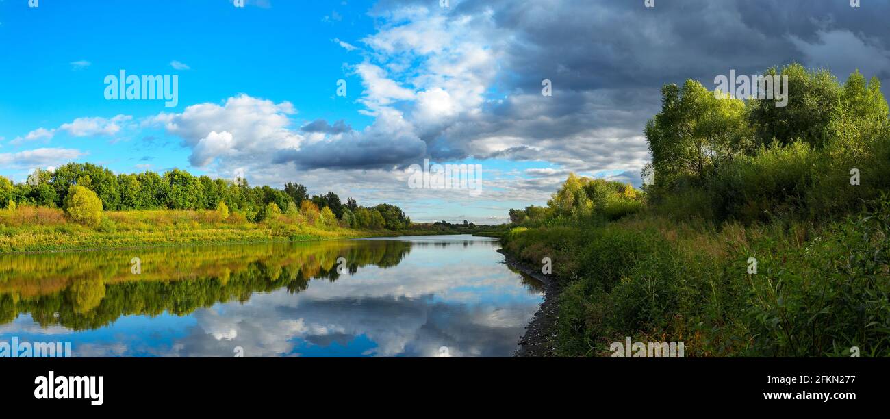Ciel dramatique orageux au-dessus du lac calme et collines verdoyantes au coucher du soleil.magnifique paysage panoramique.Beauté de la nature du soir. Banque D'Images