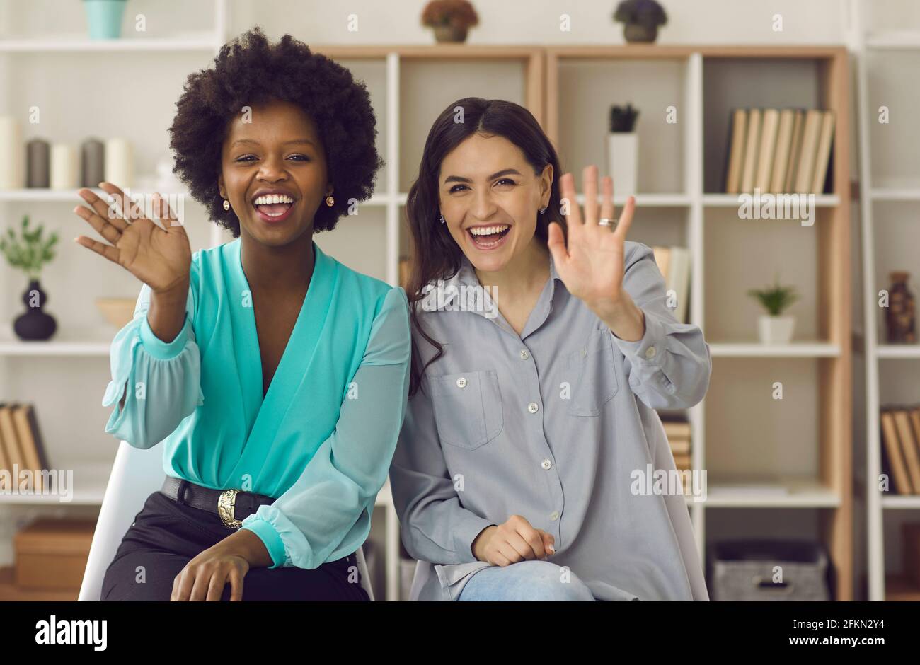 Les femmes d'affaires internationales agitant les mains saluant leurs collègues lors d'une conversation par appel vidéo. Banque D'Images