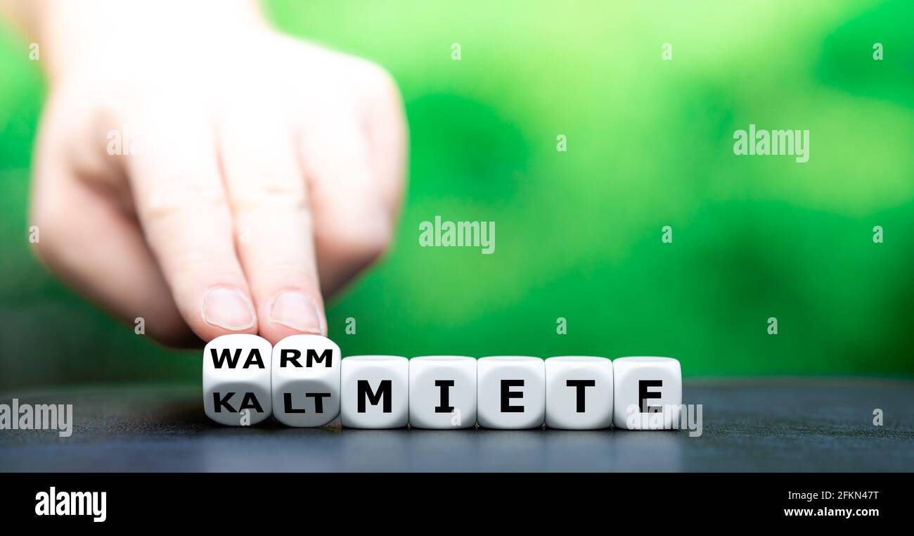 La main tourne les dés et change l'expression allemande 'kaltmiete' (loyer sans frais supplémentaires) en 'warmmiete' (loyer y compris les frais supplémentaires). Banque D'Images