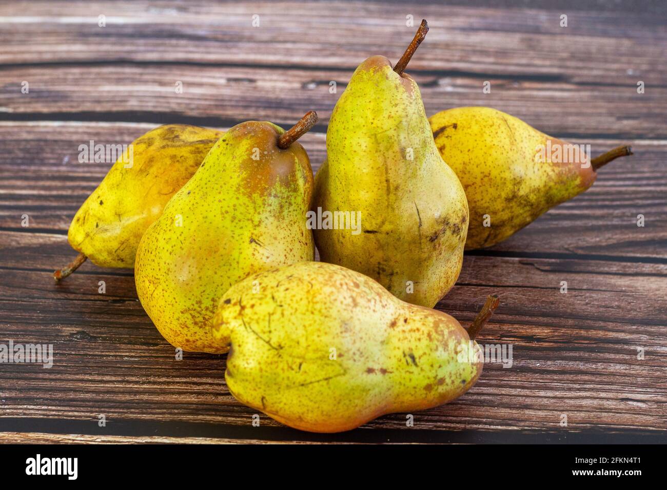 Cinq poires (Pyrus communis) de la variété Conférence sur une table rustique en bois. Banque D'Images