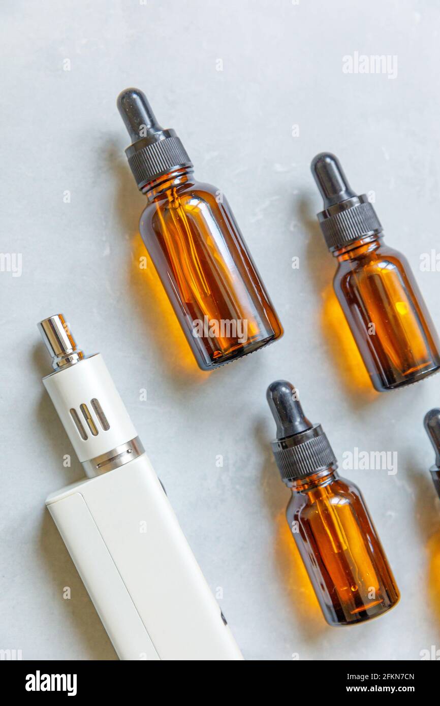 Cigarettes électroniques et bouteilles de liquide de l'appareil de Vaping sur fond gris en pierre de béton. Dispositif VAPE pour fumer de substitution. Boutique Vaping Banque D'Images