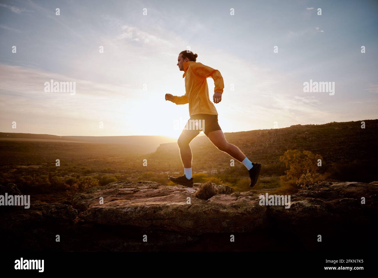 Faites monter un jeune athlète qui monte une colline au lever du soleil Banque D'Images