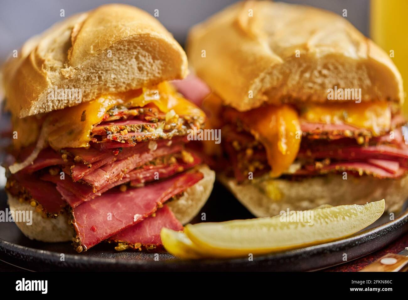 Délicieux sandwiches à la viande pastrami servis avec un verre de bière, des cornichons, des chips de pommes de terre et des accompagnements. Banque D'Images