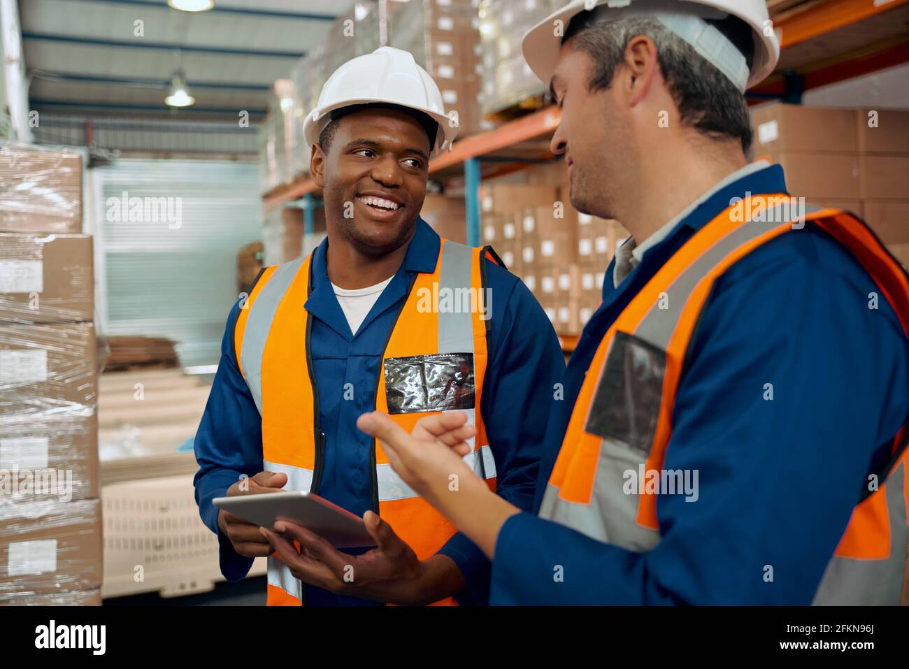 Un employé africain qui regarde son superviseur à l'intérieur d'une tablette numérique la main à l'entrepôt Banque D'Images