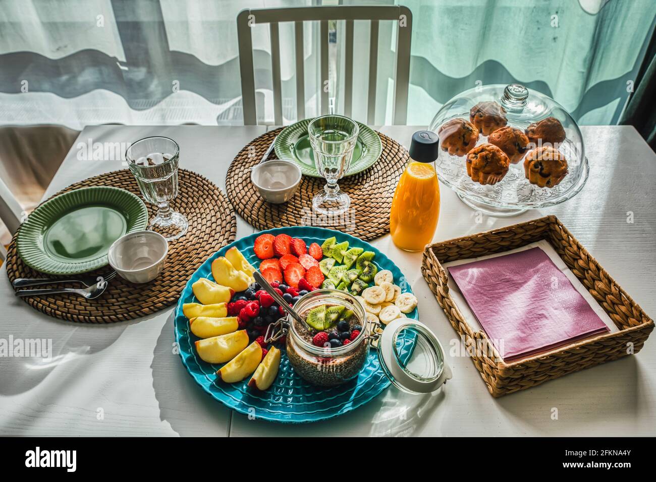 Détail des repas continentaux ou petit déjeuner ou en-cas méditerranéens avec des muffins bio et des fruits de saison sur une table en bois blanc avec des tapis rustiques Banque D'Images