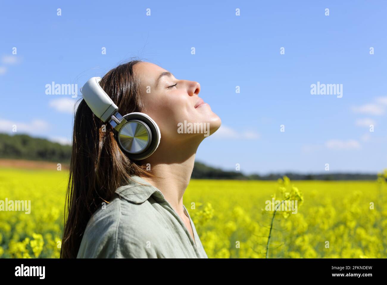 Portrait d'une femme heureuse méditant avec la technologie sans fil casque dans un champ jaune Banque D'Images