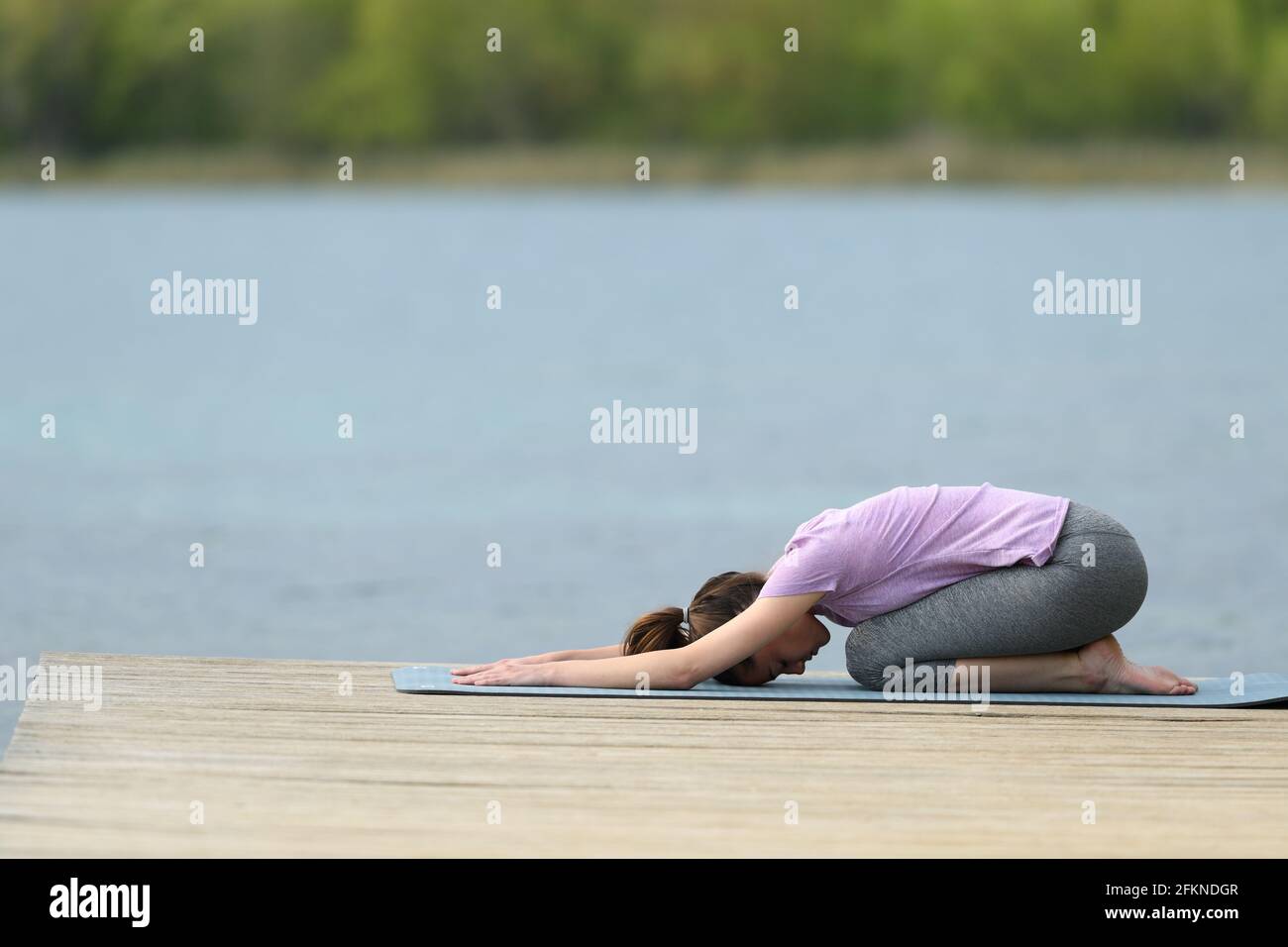 Profil d'un yogi faisant de l'exercice de yoga dans un lac jetée Banque D'Images