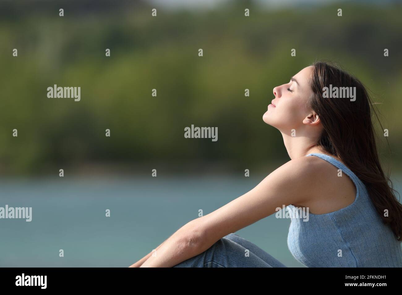 Vue latérale d'une femme détendue qui respire fraîche air dans un lac Banque D'Images