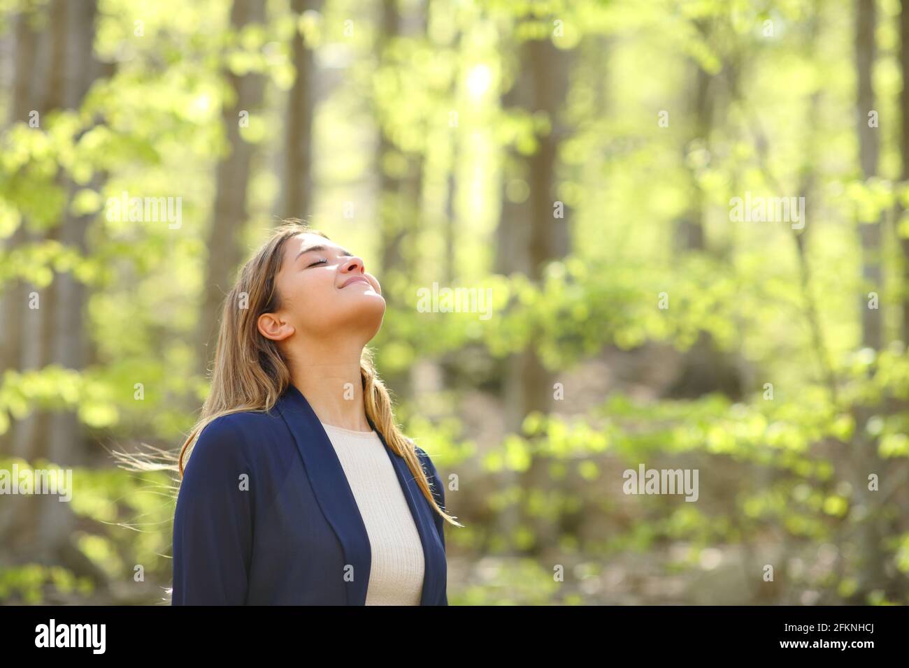Décontractée femme souffle de l'air frais dans une forêt verte Banque D'Images