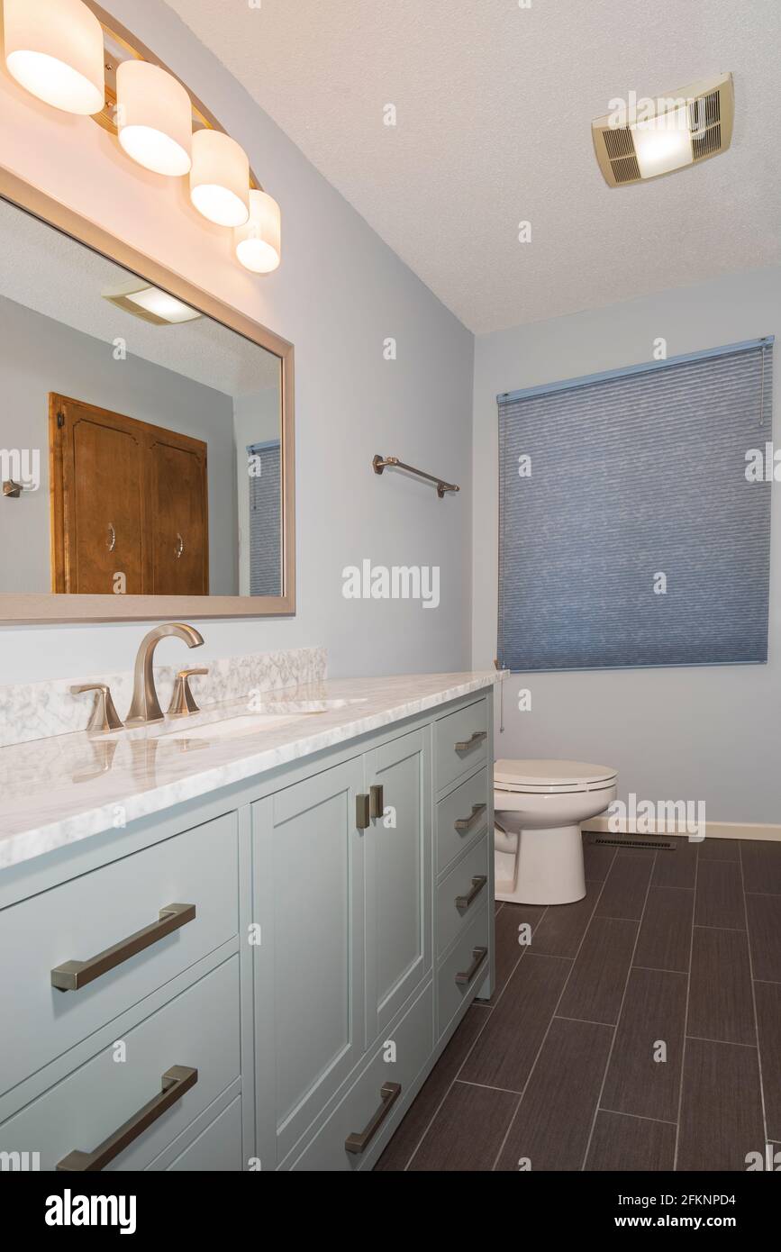 salle de bains rénovée avec meuble-lavabo et miroir de lavabo sur comptoir en marbre présentoir et toilettes Banque D'Images