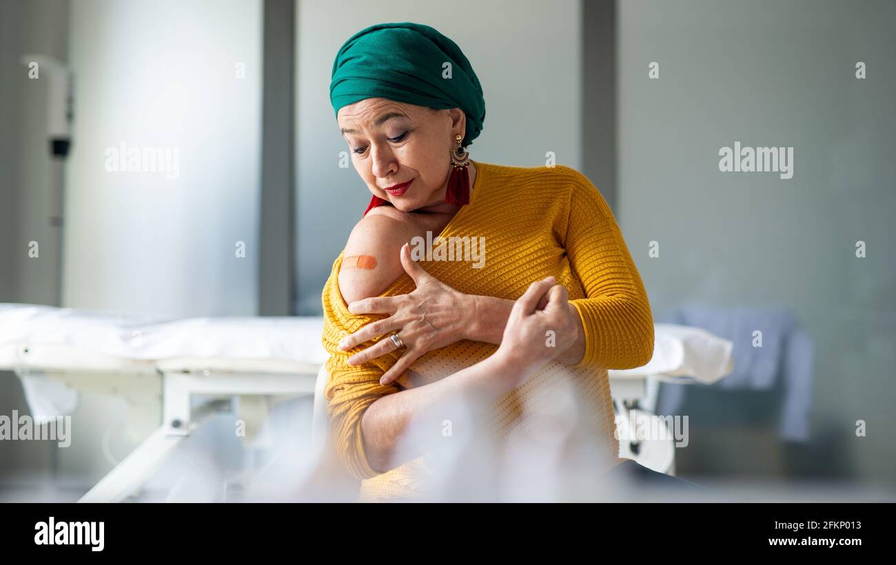 Femme âgée heureuse avec un enveloppement de tête après vaccination à l'hôpital, concept de promotion. Banque D'Images