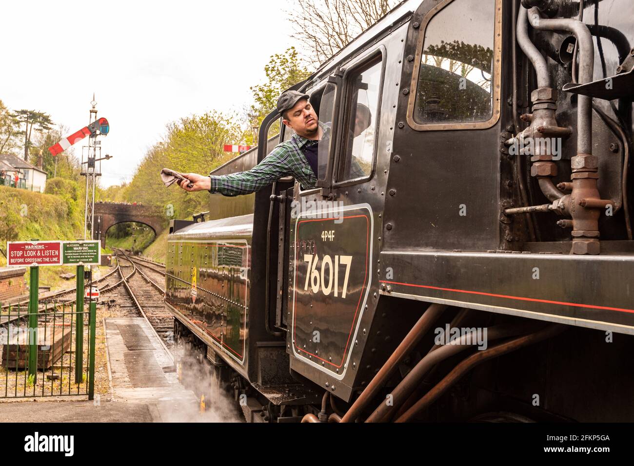 Un chauffeur de train à vapeur signale qu'il est prêt à partir sur la ligne Watercress, Mid Hants Railway, un chemin de fer à vapeur historique, Alresford, Hampshire, Royaume-Uni Banque D'Images