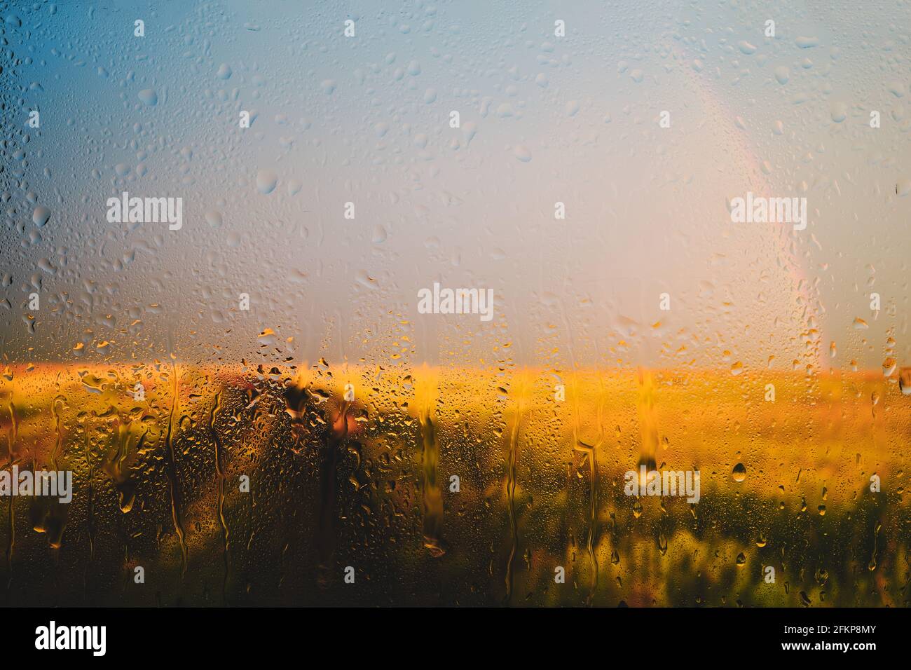 La route va dans le fond de distance d'un arc-en-ciel après la pluie vue à travers humide dans des gouttes de verre Banque D'Images