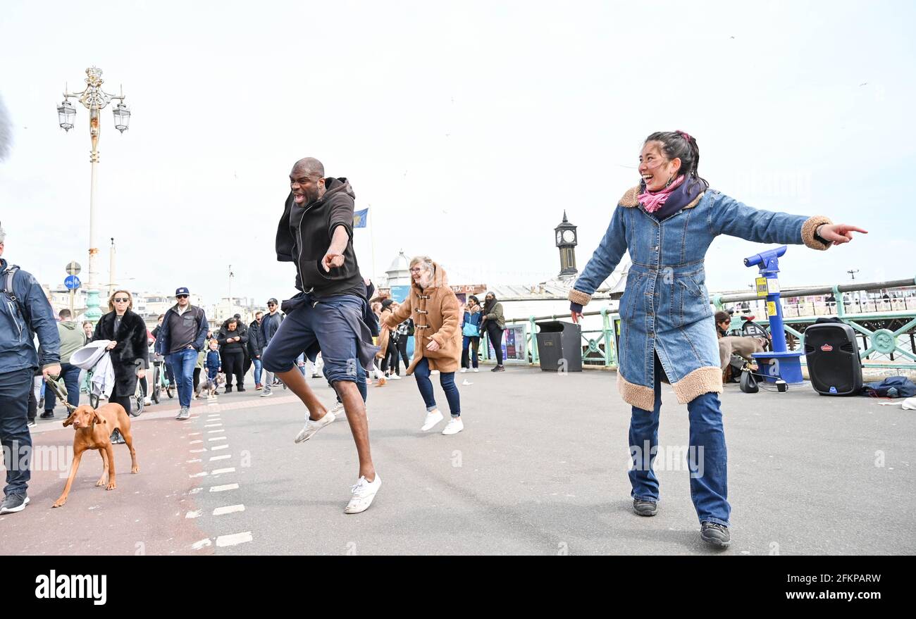 Brighton Royaume-Uni 3 mai 2021 - Dancing dans la rue sur le front de mer de Brighton que les visiteurs apprécient les vacances de mai Bank malgré le temps venteux : crédit Simon Dack / Alamy Live News Banque D'Images