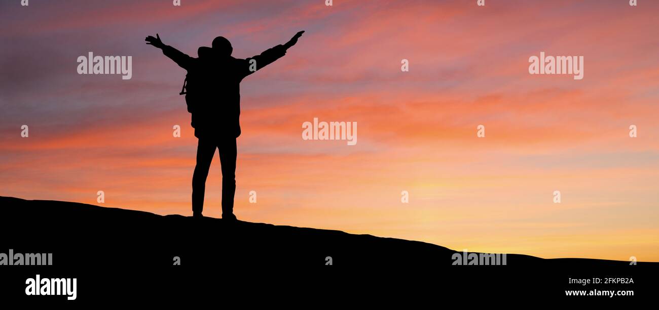 Silhouette d'un voyageur avec un sac à dos sur l'arrière-plan du ciel du coucher de soleil Banque D'Images